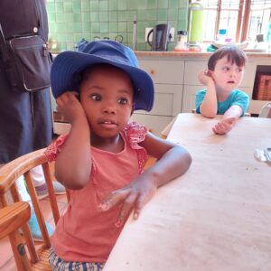 A little girl holding clay up to her ear at Clay Magic pottery studio.