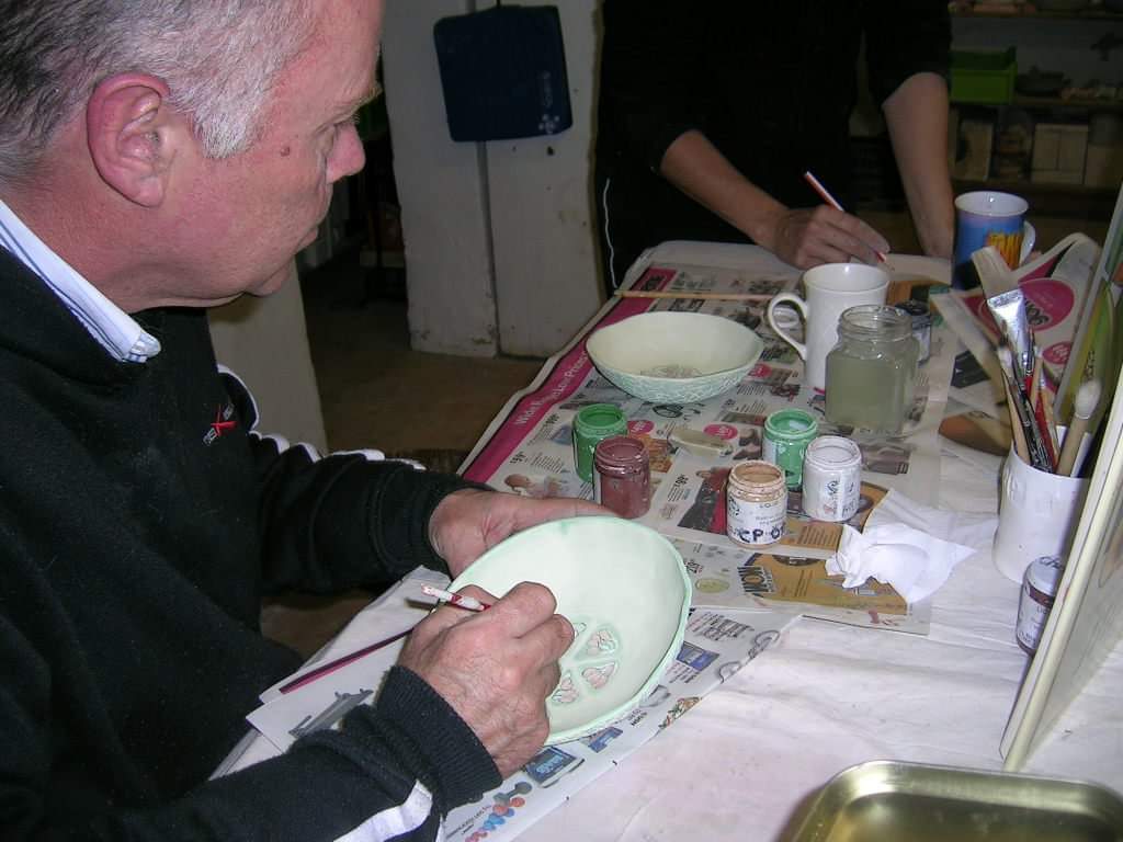 Adult student working on intricate pottery designs at Clay Magic studio.