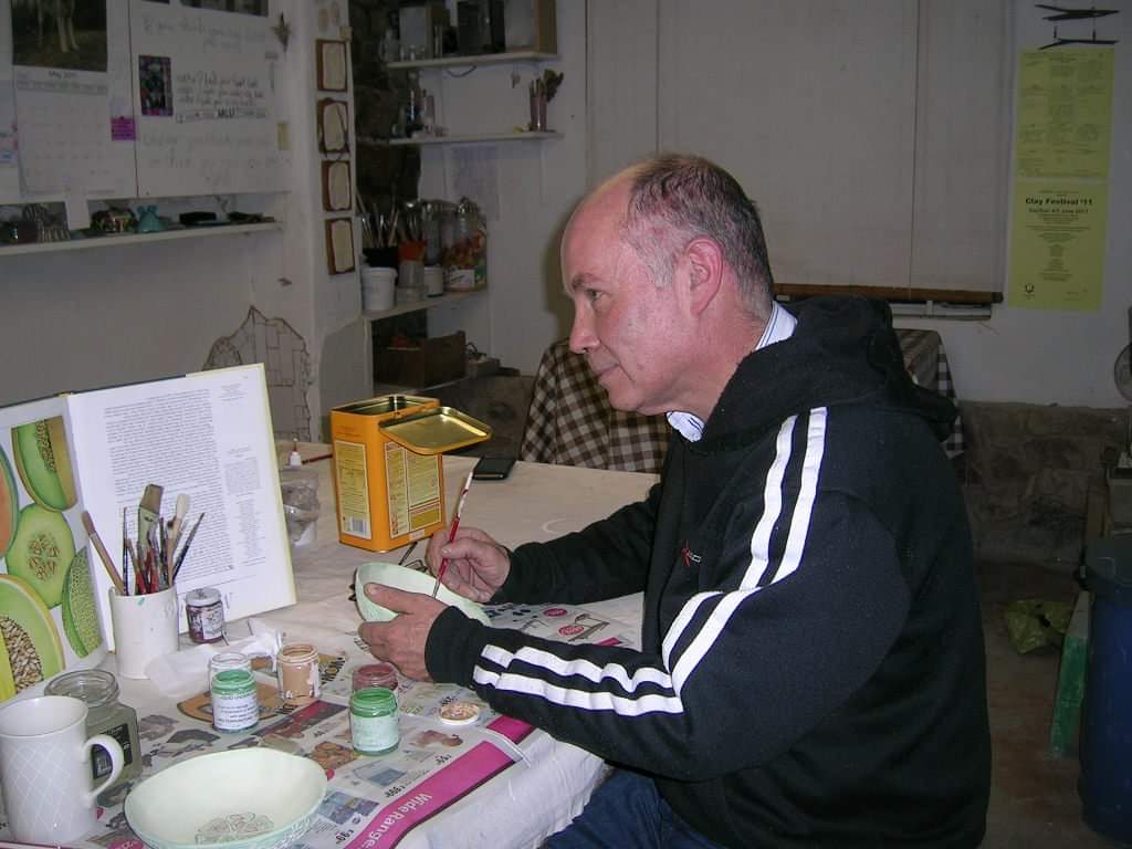 Student painting clay at Clay Magic pottery studio, focused on their creation.