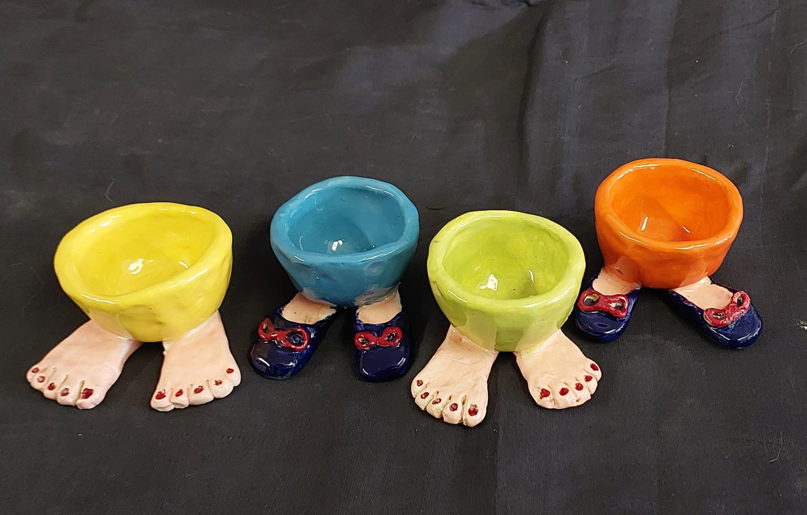 Colourful egg cups with feet made by a student at Clay Magic pottery studio.