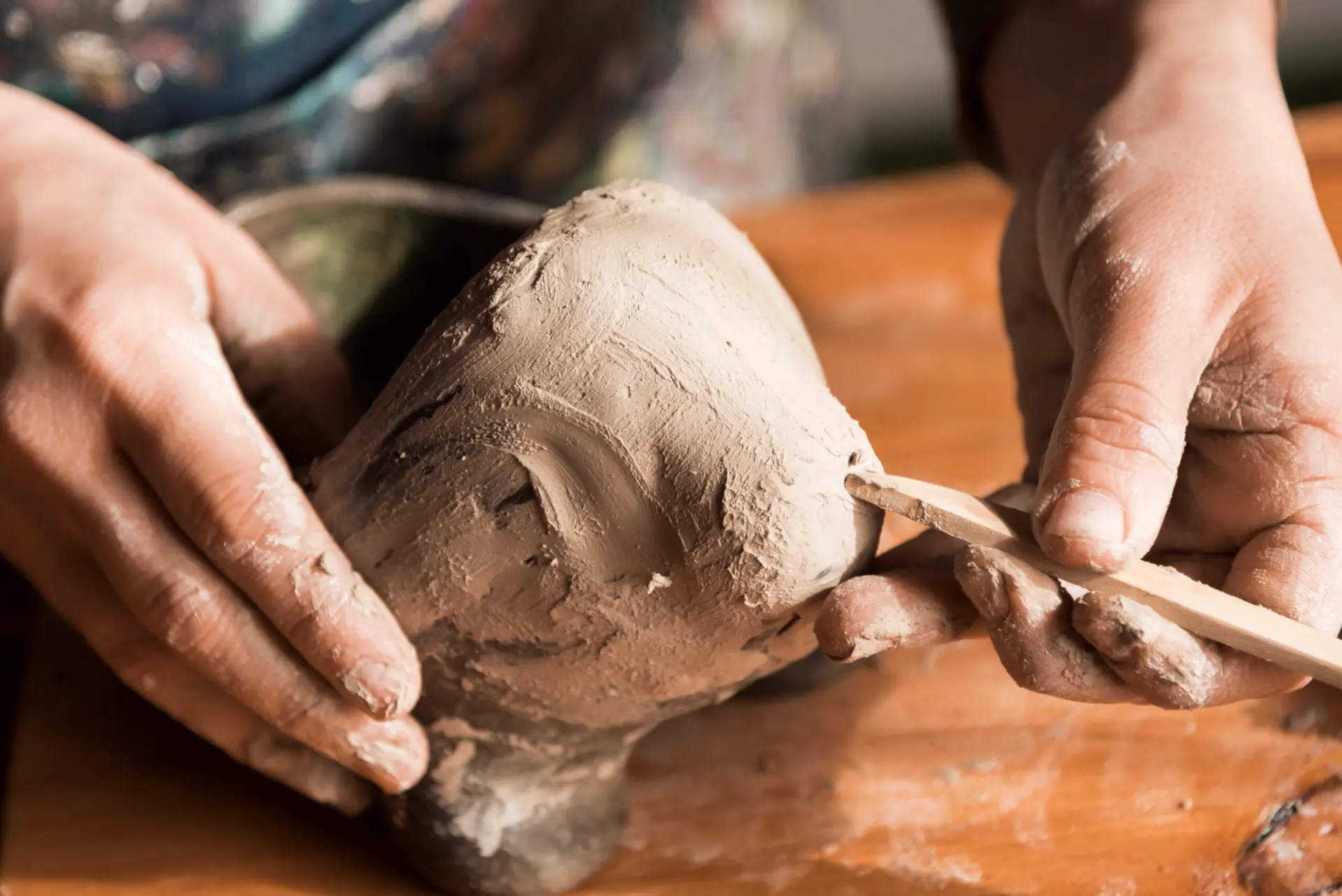 Student shaping clay at Clay Magic pottery studio.