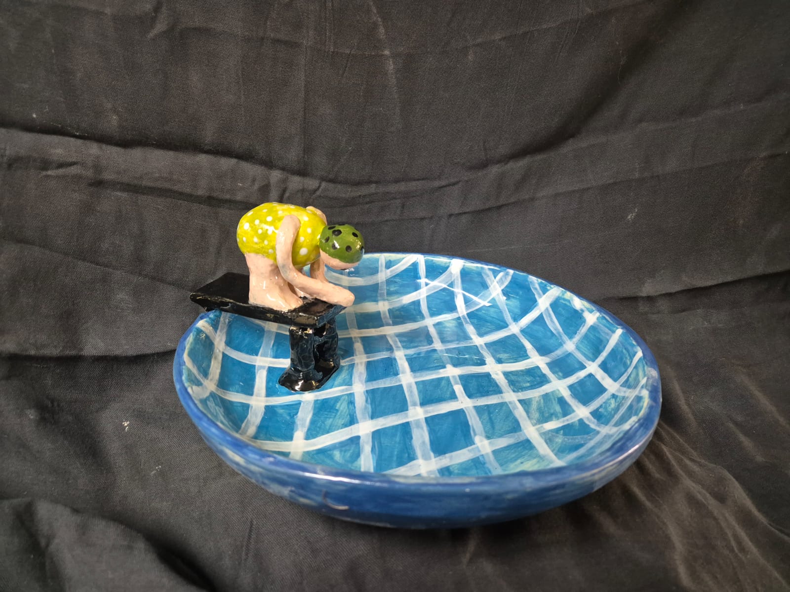 Whimsical blue clay bird bath with a diving board.