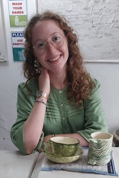 Student in green with her handmade green pottery pieces at Clay Magic studio.