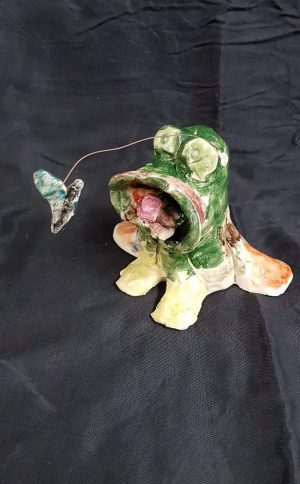 Pottery frog and fly sculptures created by a student at Clay Magic studio.