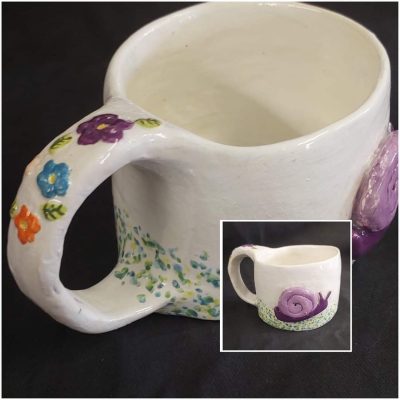 Pottery mug with flowers, created by a young student at Clay Magic studio.