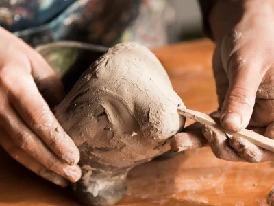 Student shaping clay at Clay Magic pottery studio.